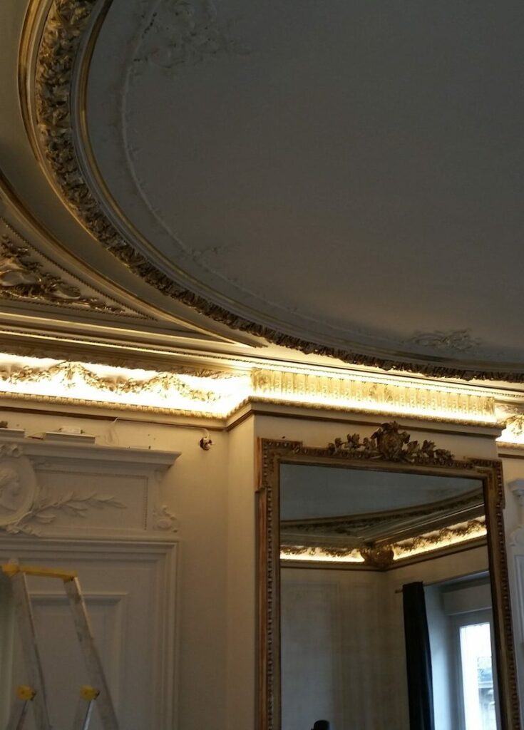 Intérieur élégant avec miroirs ornés et plafond décoré, éclairage chaud et reflets dorés sur les murs. écran led transparent vitrine boutique visible?