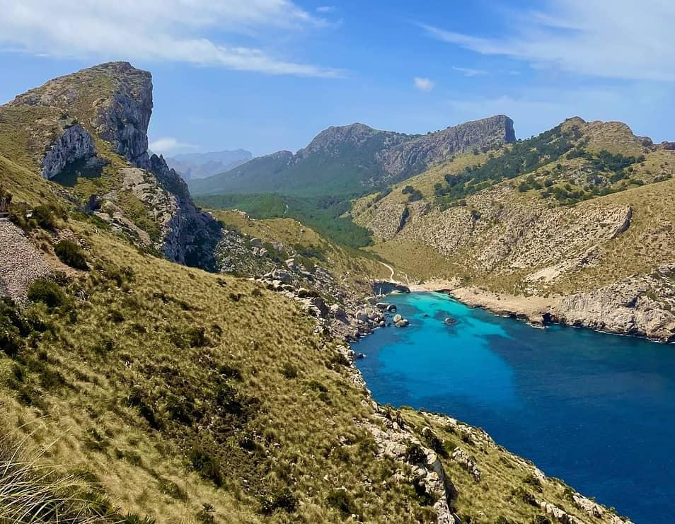 Vue des collines et crique azurée au cœur de la campagne aux Baléares, entre montagnes et mer turquoise.