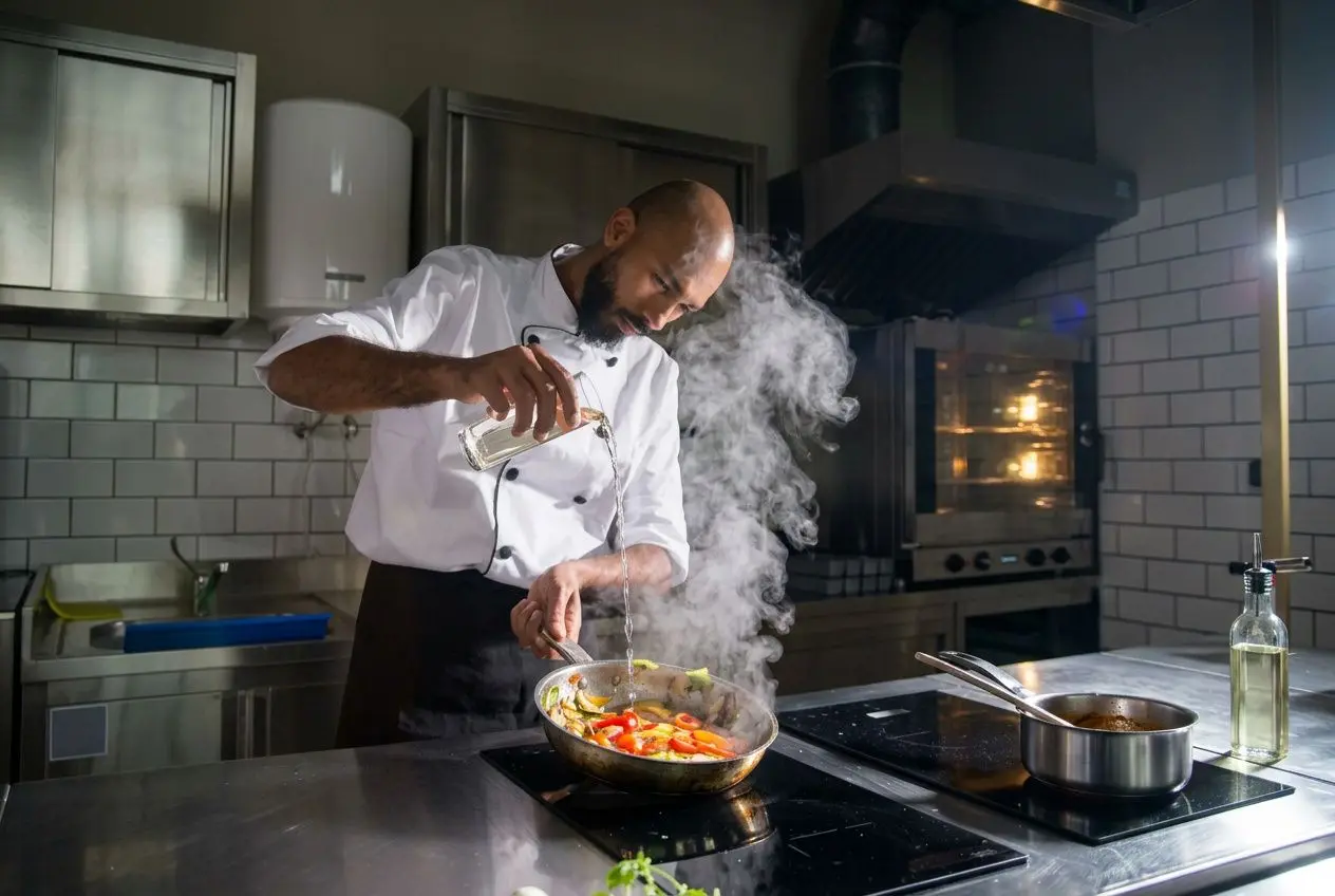 Chef cuisinant à feu vif, ajoutant de l’huile dans une poêle inox sur la plaque, vapeur et légumes sautés visibles. Integrate keyword: comment culotter une poêle inox naturally. But must include keyword exactly? The instruction: integrate main keyword naturally. Include phrase: "comment culotter une poêle inox" within the description. Let's craft: "Chef cuisinant dans une cuisine pro, montrant comment culotter une poêle inox en ajoutant de l’huile et des légumes qui flambent" But must be accurate: The image shows man pouring liquid and steam; vegetables in pan. We'll do: "Chef en cuisine professionnelle cuit des légumes dans une poêle inox, montrant comment culotter une poêle inox via l’ajout d’huile et fumée parfumée." Ensure length 125 chars. Let's count: "Chef en cuisine professionnelle cuit des légumes dans une poêle inox, montrant comment culotter une poêle inox via l’ajout d’huile et fumée." That's long. Let's produce ~110 chars. Let's craft final: "Chef en cuisine pro cuit des légumes dans une poêle inox, illustrant comment culotter une poêle inox avec de l’huile et vapeur." Chef en cuisine pro cuit des légumes dans une poêle inox, illustrant comment culotter une poêle inox avec de l’huile et vapeur.
