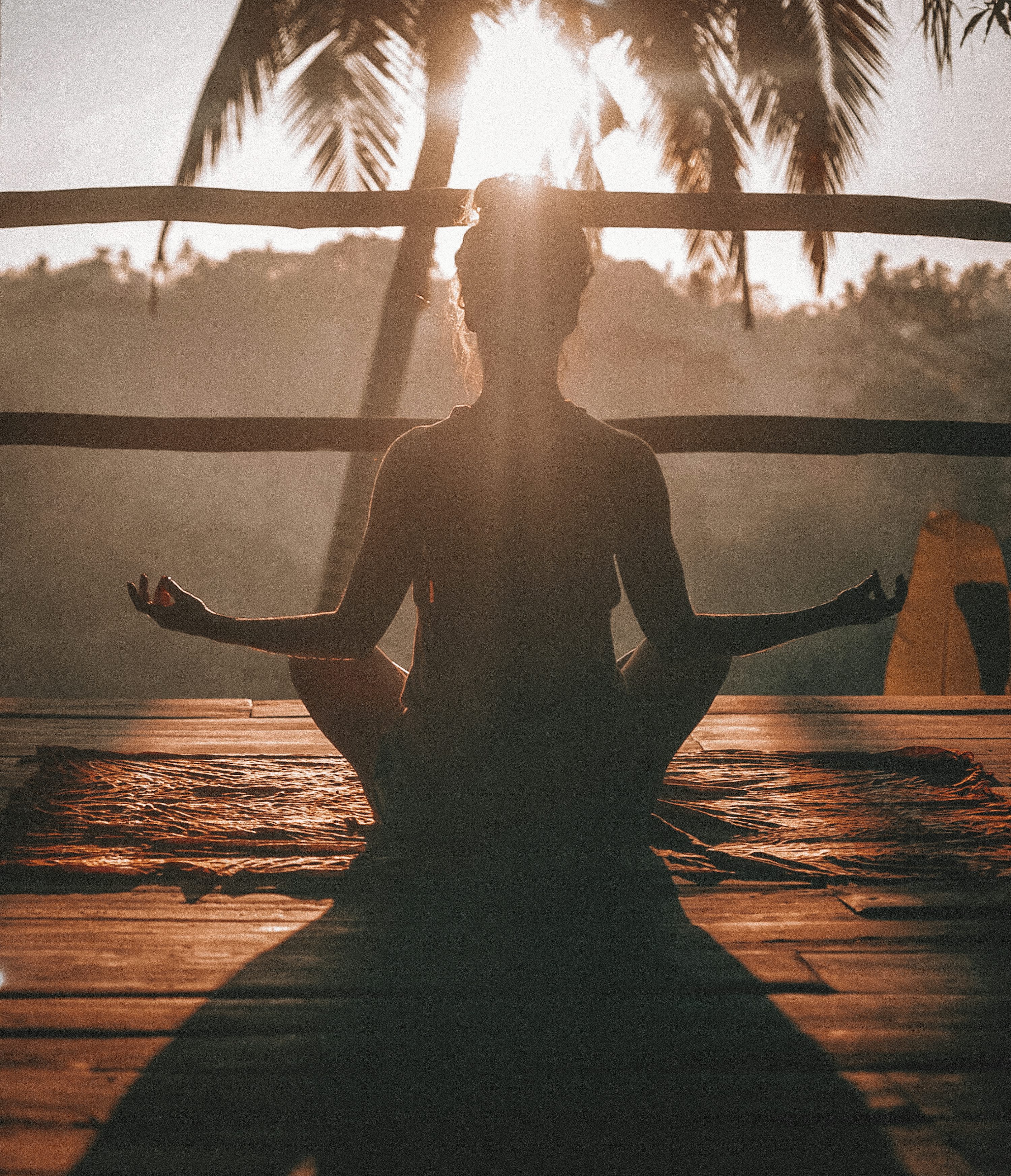 Person practicing yoga meditation on a quiet beach at sunset, illustrating the calming effect of the sea.