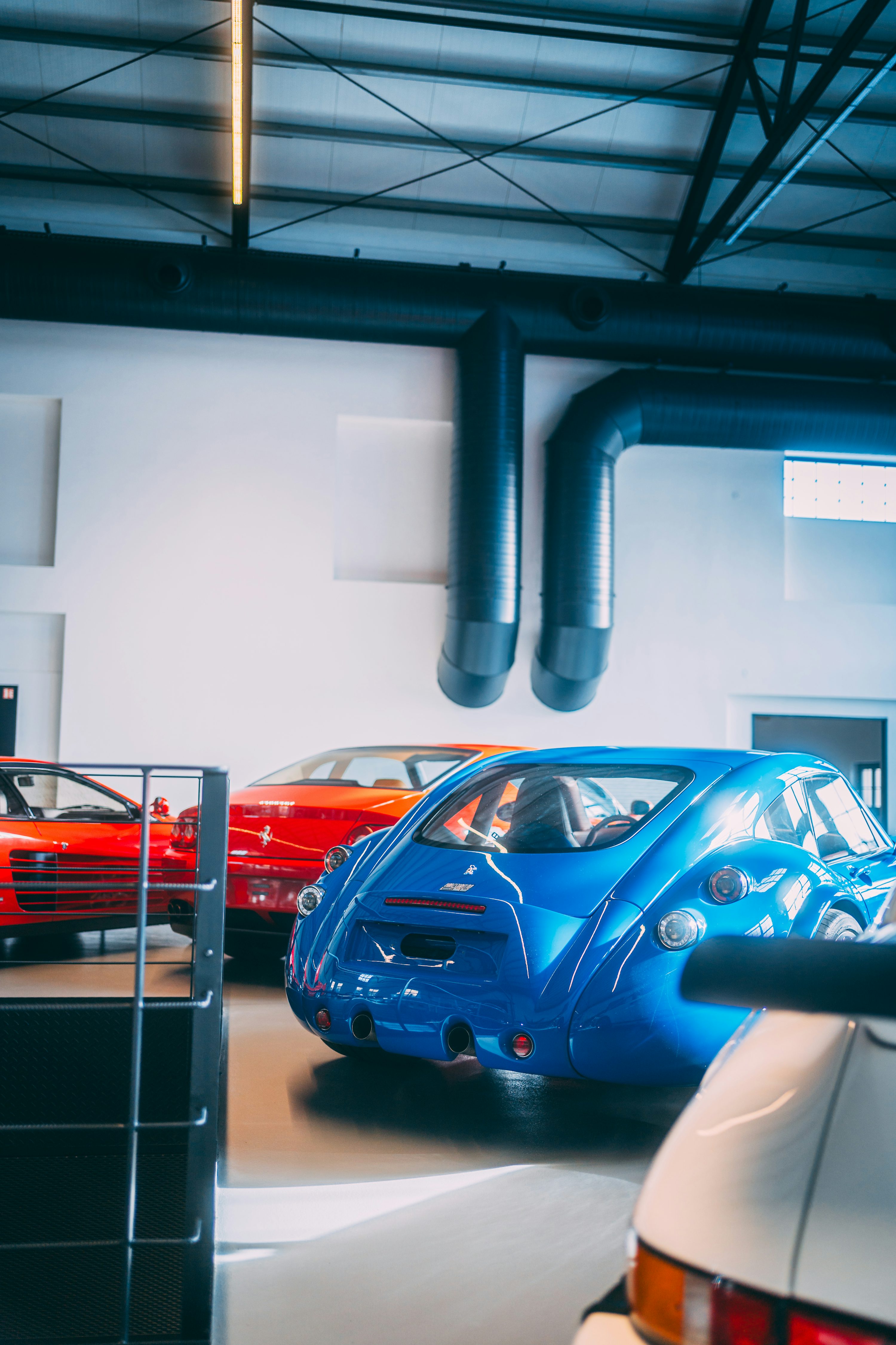 Mehaničar dela na avtomobilu v garaži z odprtim prostorom motorja in diagnosticno opremo v bližini, kar prikazuje optimizacijo ECU-ja na modernih avtomobilih.