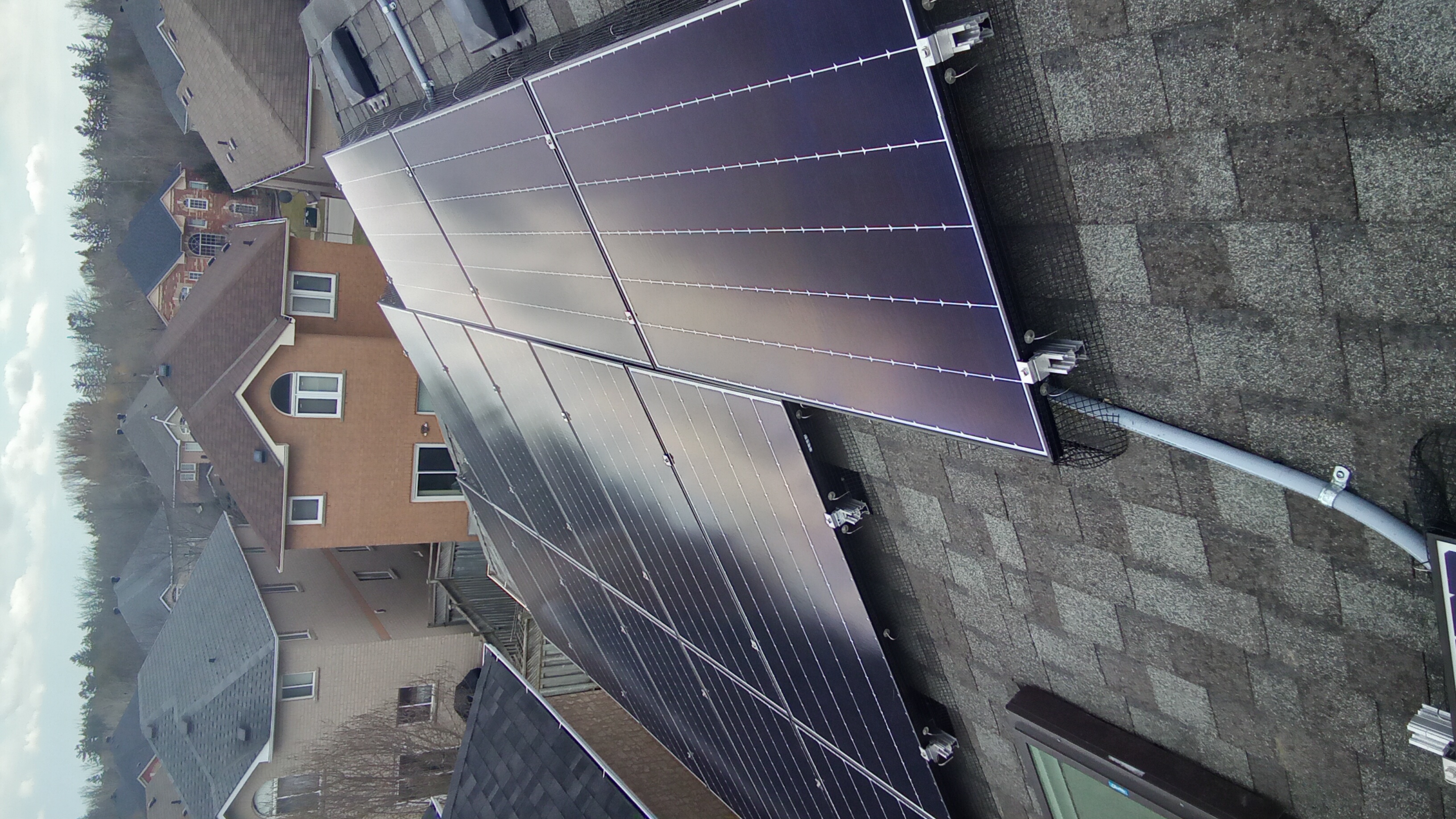 Rooftop solar panels installed on a sloped roof, connected with mounting rails and wiring.