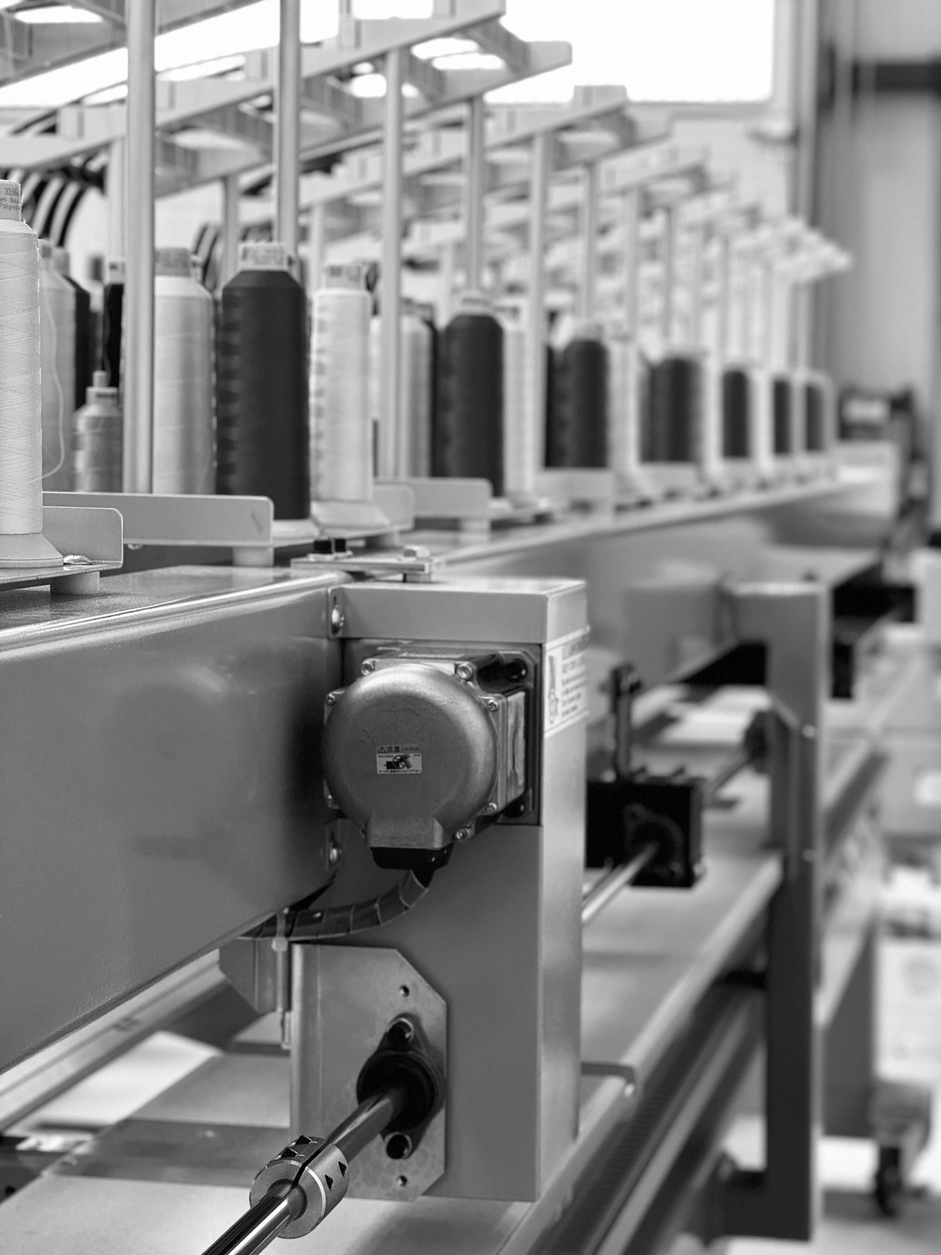 Machine de fabrication textile avec consoles et bobines en série dans une usine.