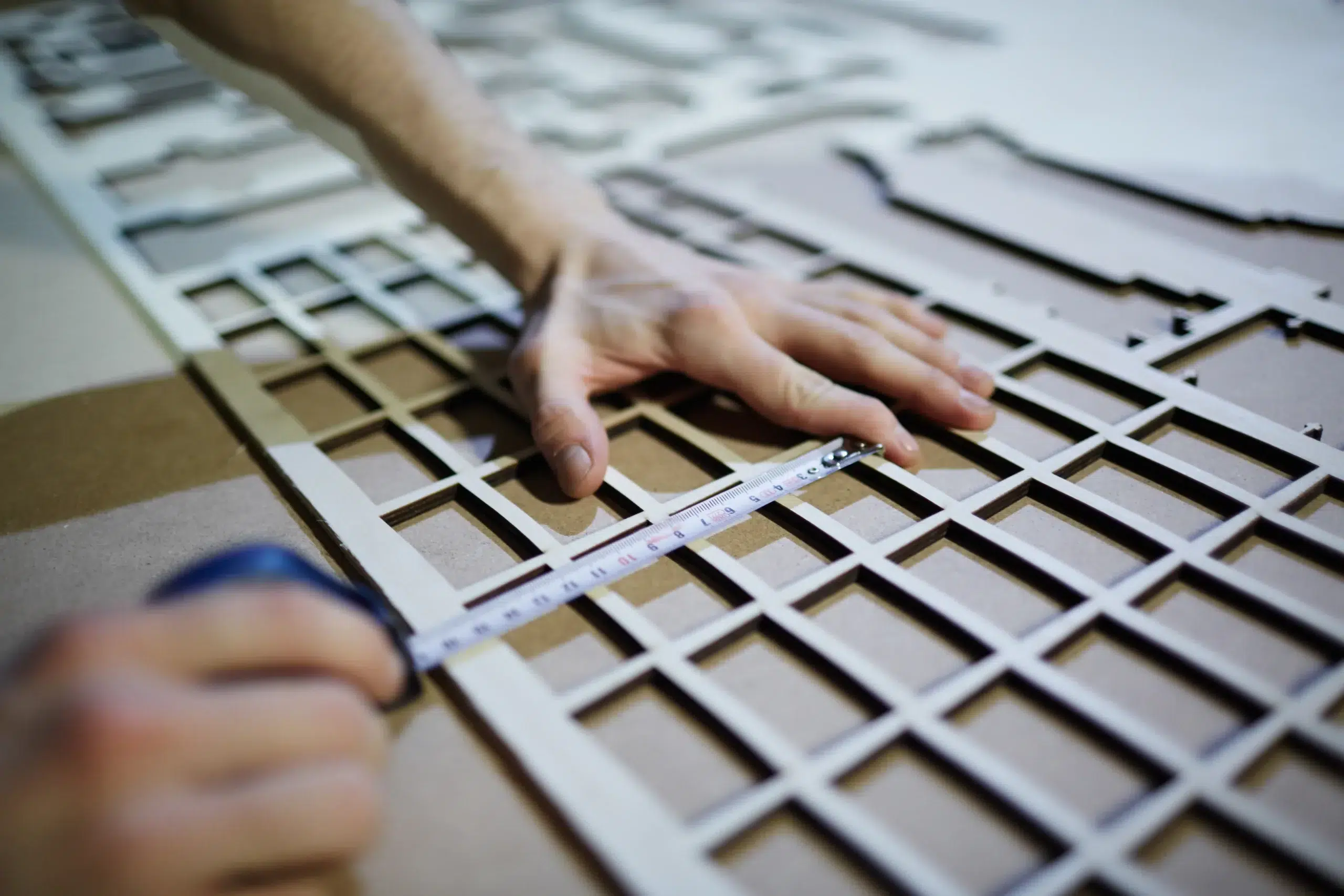 Person marking a grid pattern with a measuring tape and pencil, aligning inner sections for precise fit. interior shutter installation tools needed to fit shutters