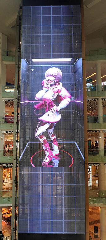 Figure montrant une sculpture robotisée humanoïde dans une colonne vitrée d’un centre commercial, entourée d’échelles et de rayonnages. intégrer le mot-clé: réparer pixel bloqué? The instruction says integrate keyword naturally when provided. Provide ALT text including "réparer pixel bloqué" naturally. Let's craft: "Sculpture robotique dans une colonne vitrée d’un centre commercial; démonstration futuriste prête à inspirer des conseils pour réparer pixel bloqué." But should describe visible: robot-like figure inside glass column with grid pattern. Ensure length 50-125 chars. Let's produce: "Sculpture humanoïde robotique dans une colonne vitrée d’un centre commercial, thème proche de répare pixel bloqué." Hmm awkward. Better: "Sculpture robotique dans une colonne vitrée d’un centre commercial; idée de réparer pixel bloqué évoquée par l’esthétique technologique." Include keyword exactly "réparer pixel bloqué". Let's craft final: "Sculpture robotique dans une colonne vitrée d’un centre commercial; exemple visuel évoquant réparer pixel bloqué et l’affichage numérique." Check length ~140. Need <=125. Let's shorten: "Sculpture robotique dans une colonne vitrée d’un centre commercial; image évoquant réparer pixel bloqué et l’affichage numérique." Count chars ~110. Good. Output only that. But ensure it's accurate: it's a robot in a glass column with grid. Okay. Include keyword integrated: "évoquant réparer pixel bloqué". Fine. Let's output.