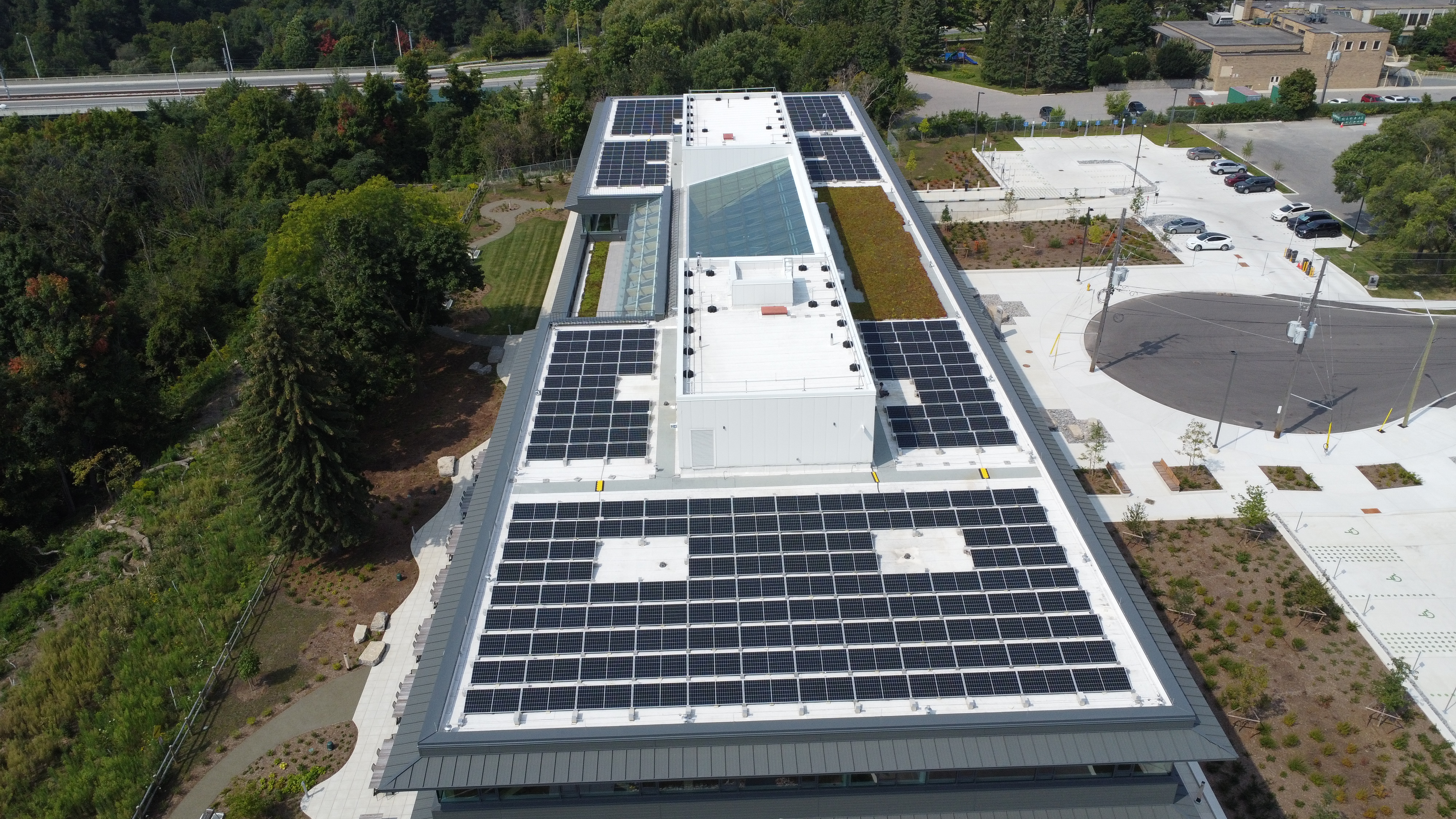 An aerial view shows rows of solar panels on a large flat roof.