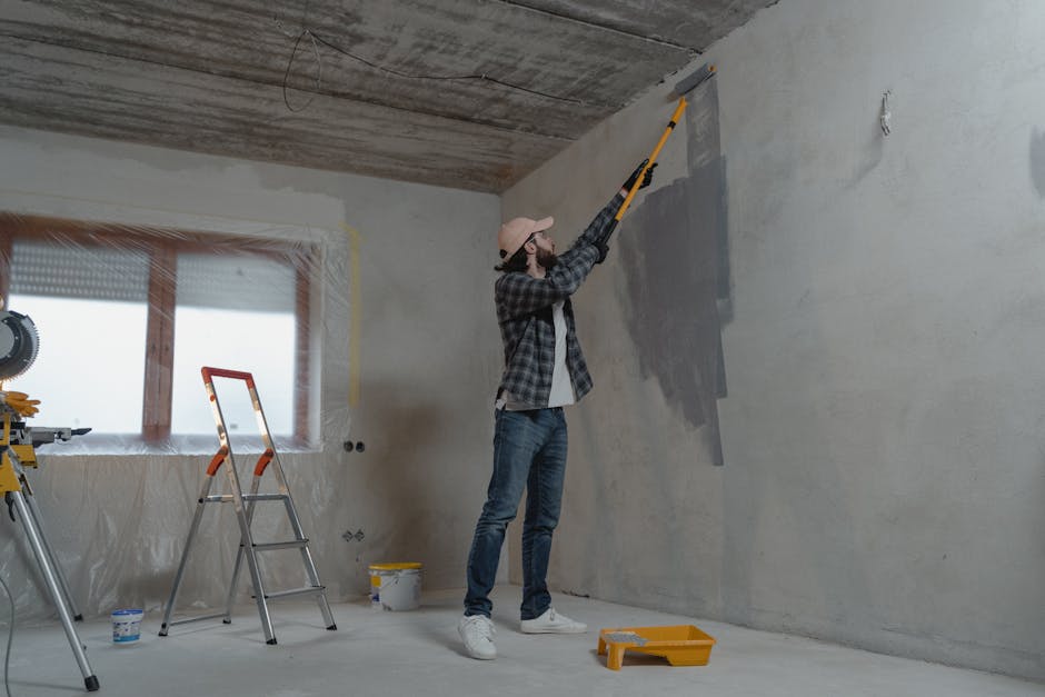 Un homme en train de peindre un mur intérieur avec un rouleau lors d'un projet de rénovation.