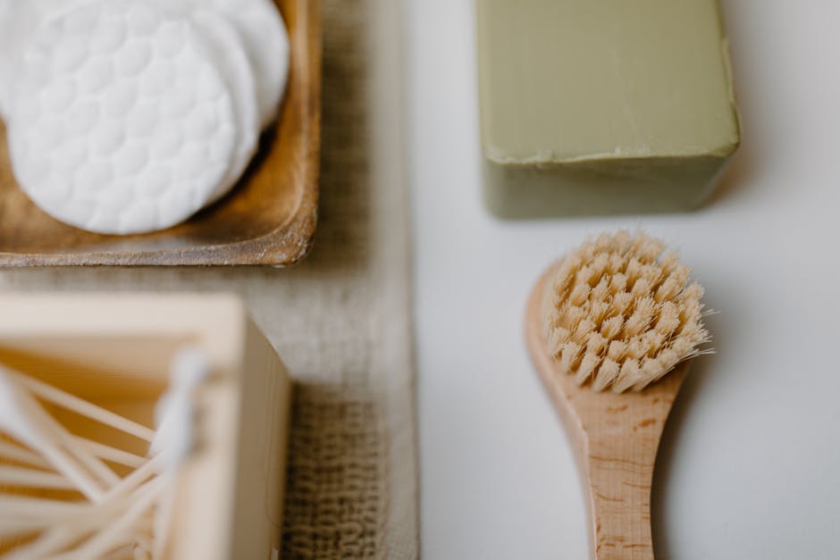 Close-up of eco-friendly bath products including soap and brush on a neutral background.