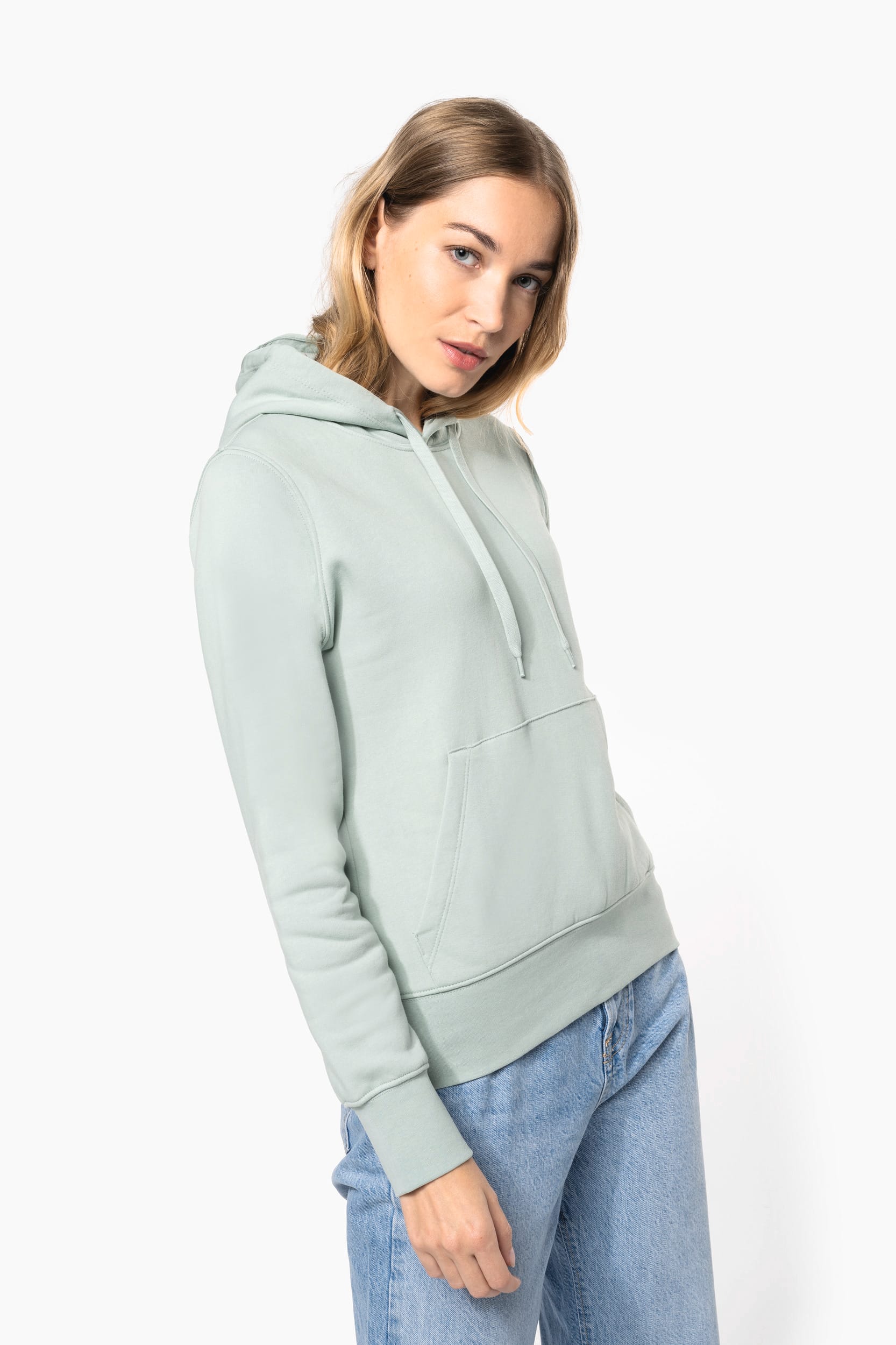 Homme ou femme portant un sweat à capuche vert pâle avec poche kangourou et cordons sur fond clair.