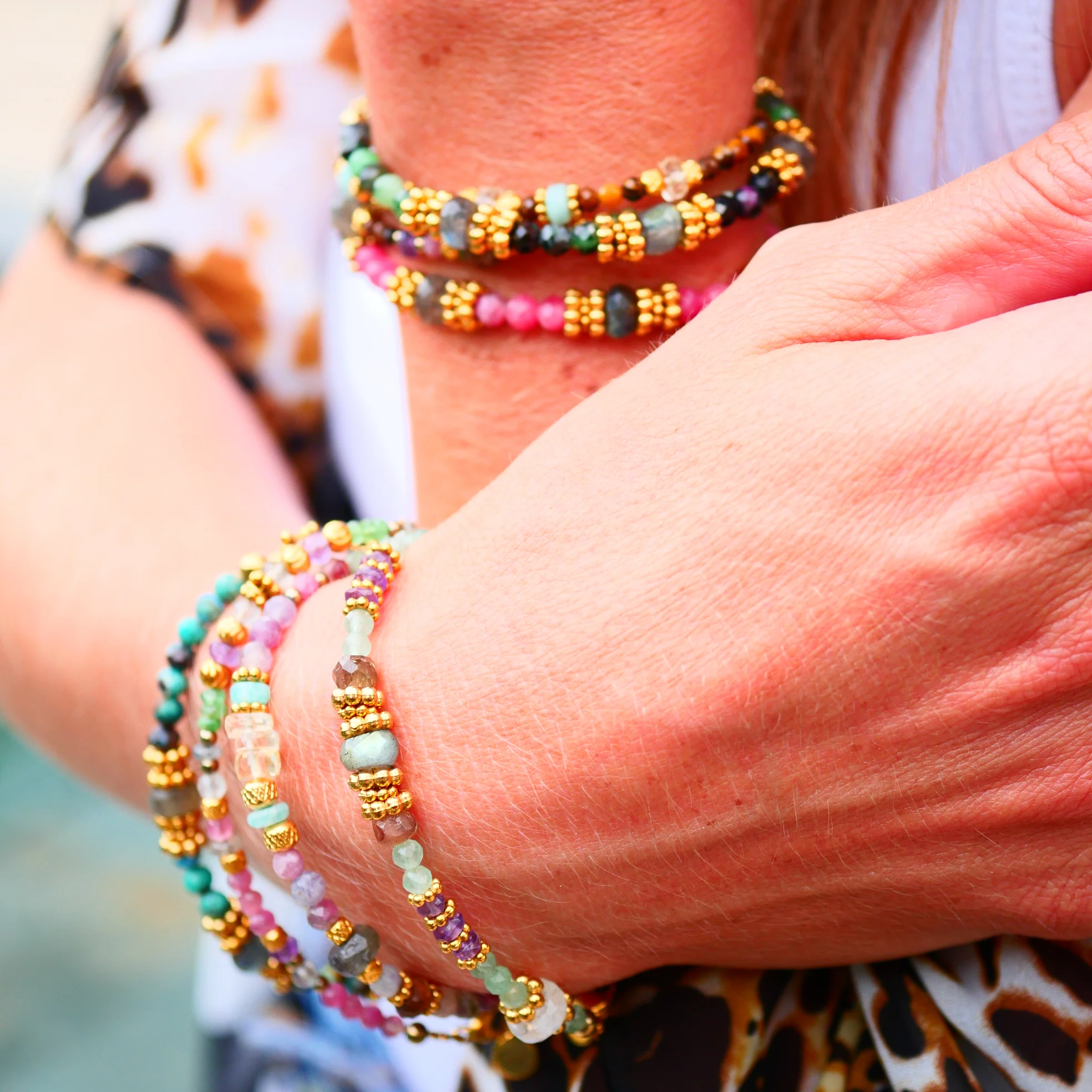 Bracelets colorés en pierres naturelles et perles dorées sur poignet, bijoux talismans artisanaux de Ginandger.