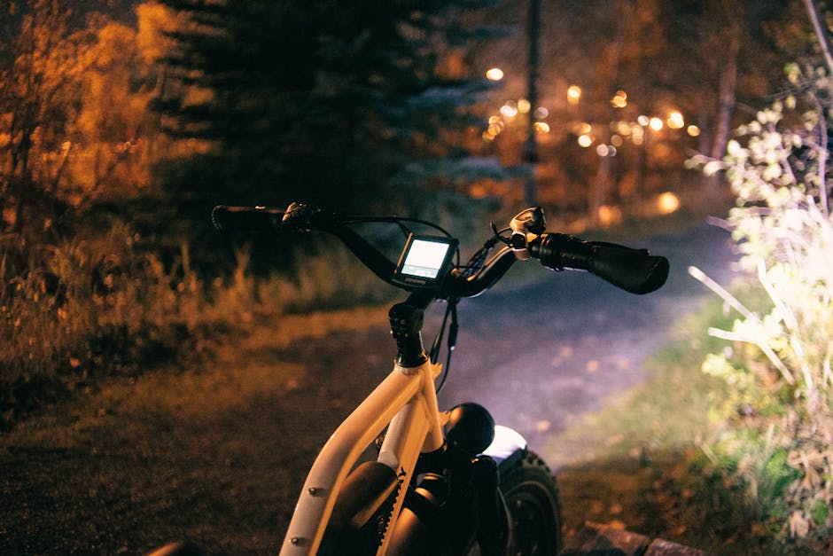 Cycliste avec un phare éclairant un sentier forestier la nuit.