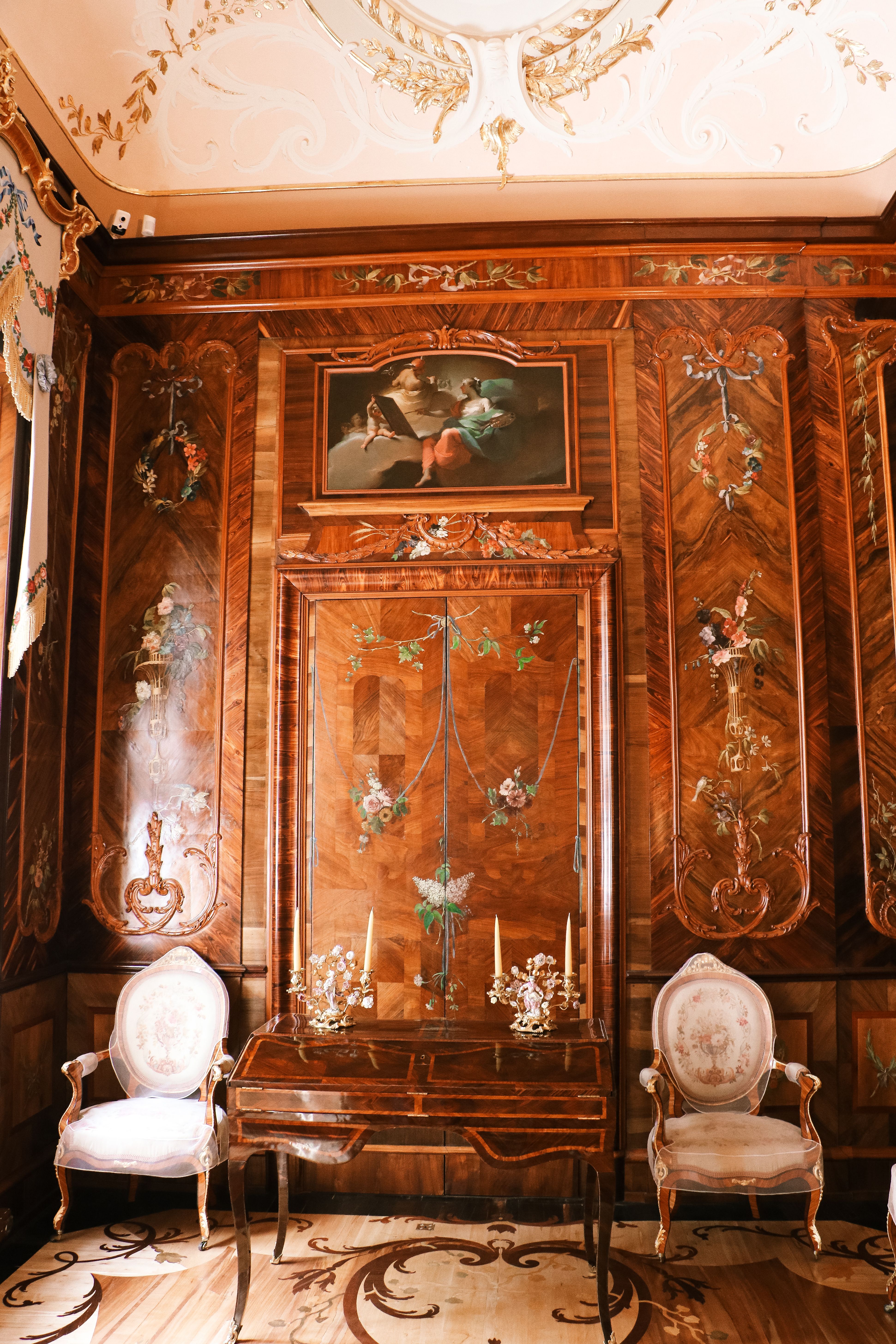 Interni di stile classico con mobili in legno pregiato, sedie imbottite e tavolo da scrittoio al centro, decorazioni floreali e cornici ornate. arredo classico.
