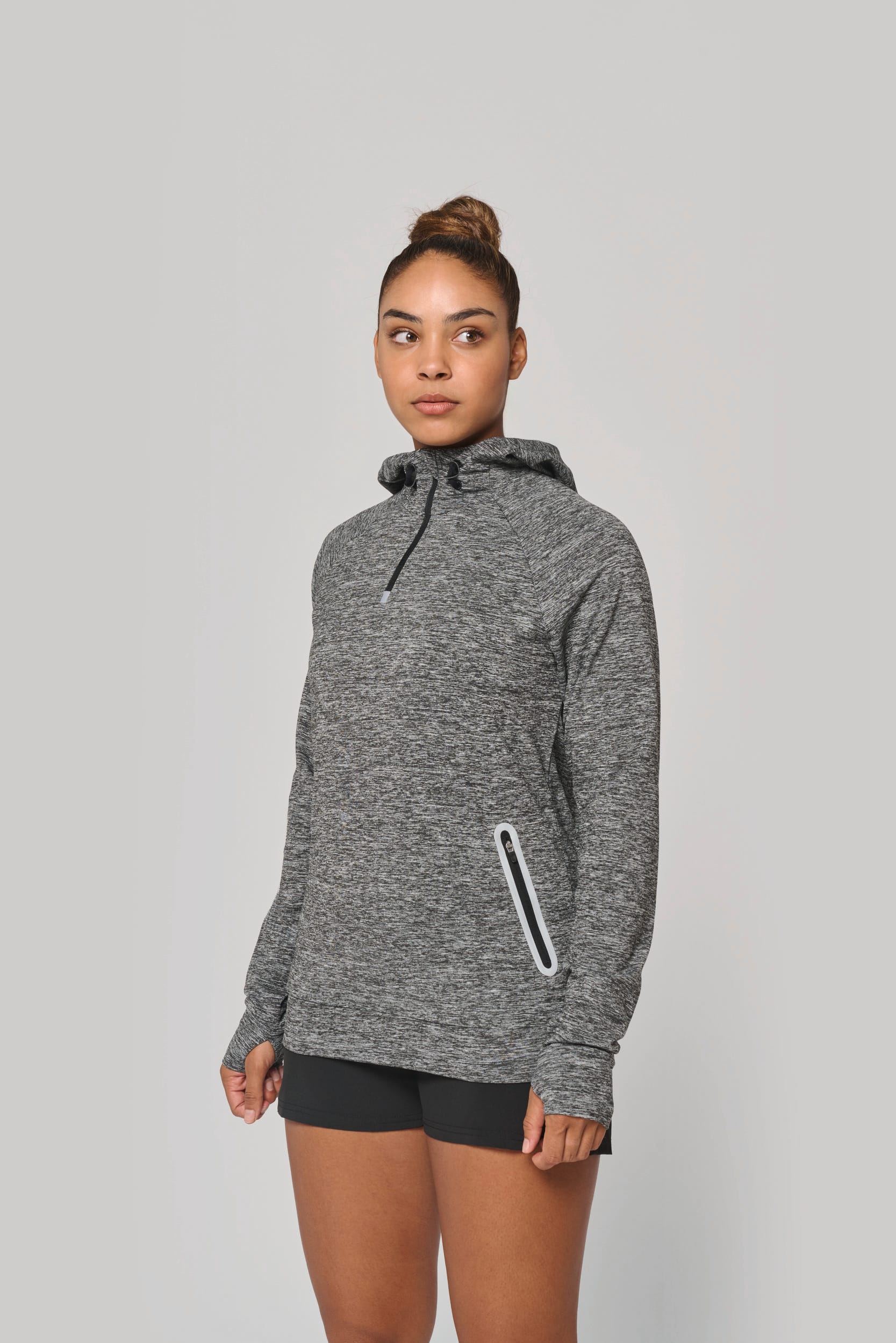 Homme ou femme portant sweat à capuche gris chiné, poche zippée sur le côté, tenue décontractée. trou ves rapidement un prestataire à paris pour commander des pulls et sweats personnalisés