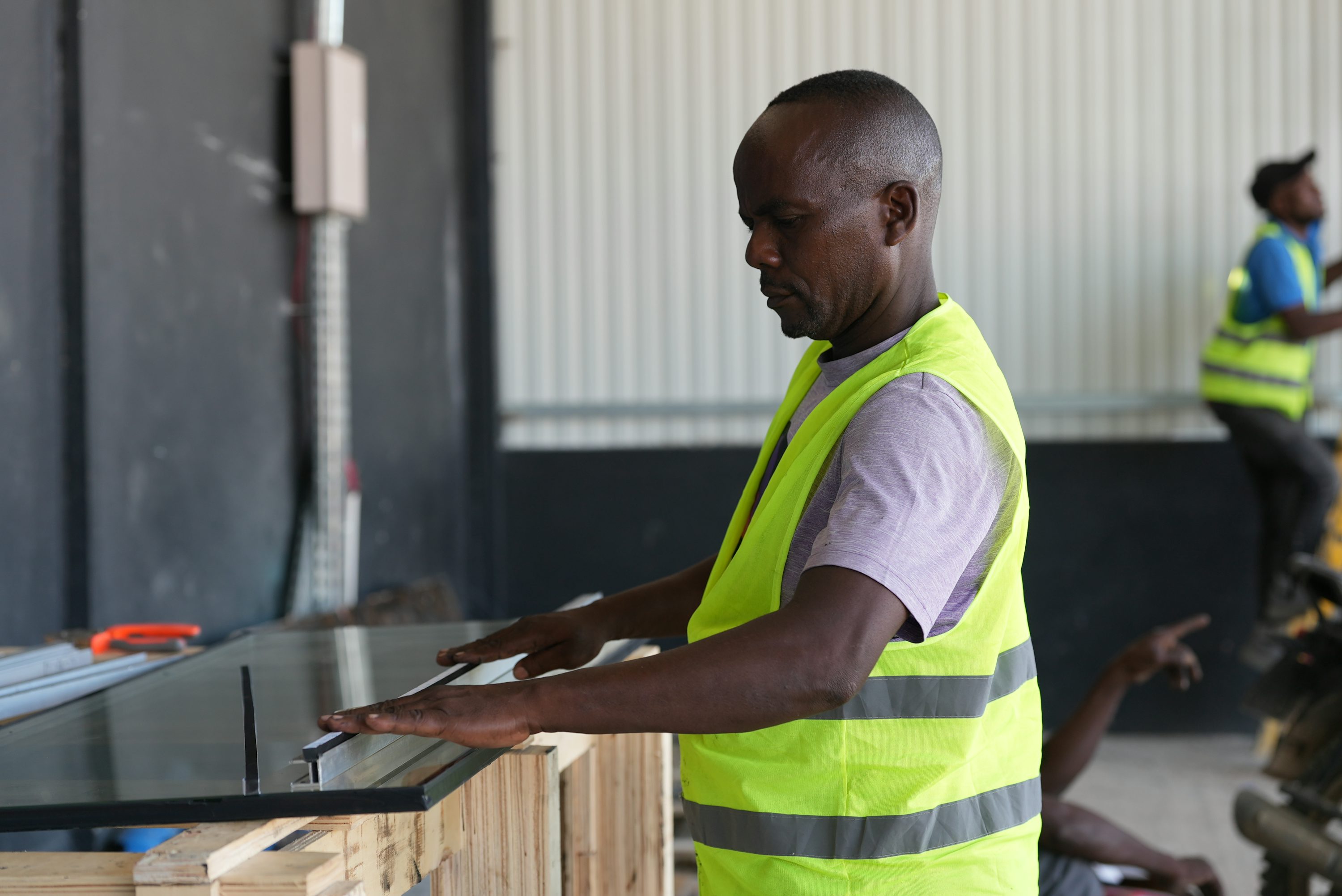 Ouvrier en gilet haute visibilité jaune fluo à bandes réfléchissantes travaillant dans un atelier
