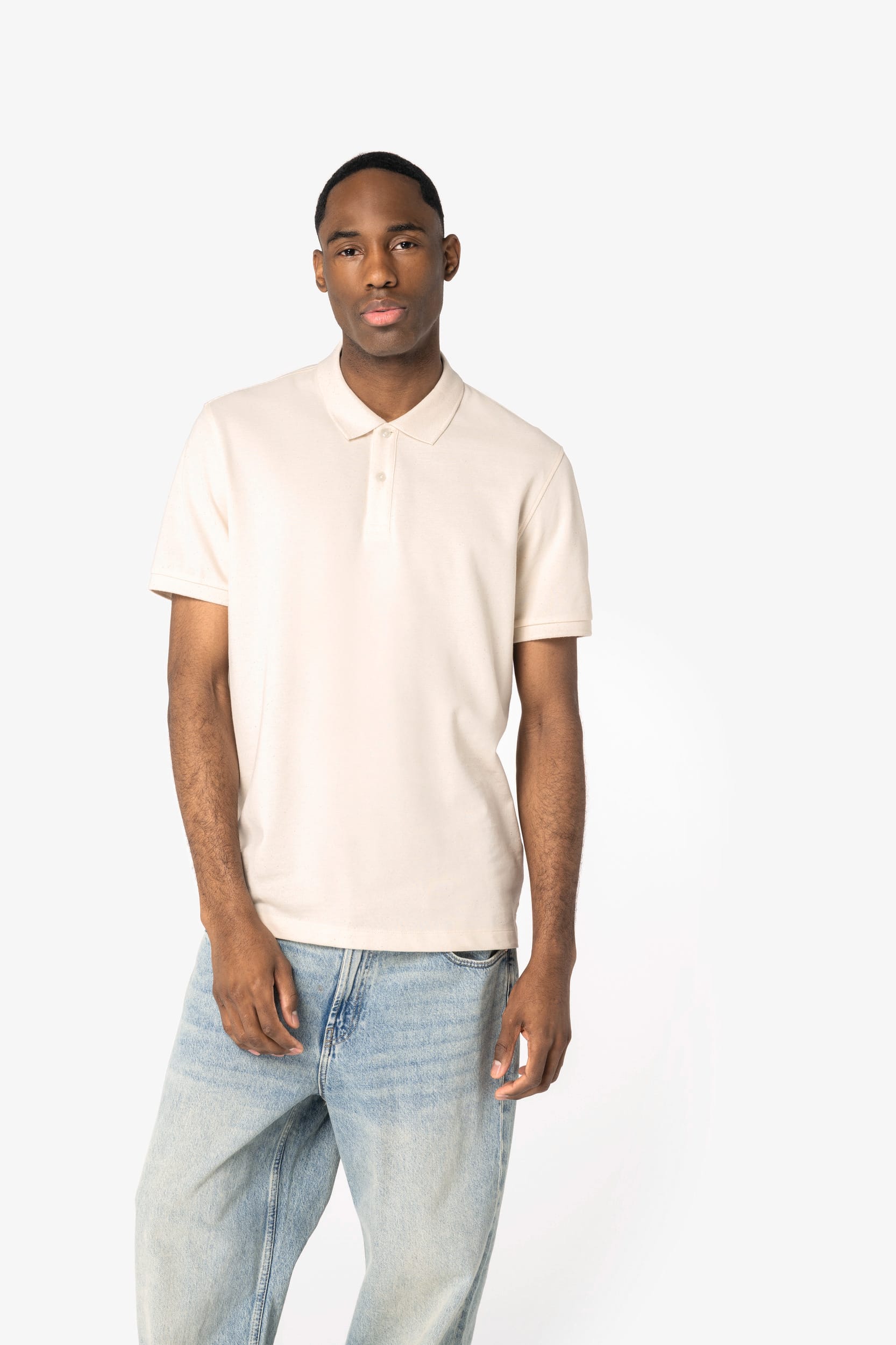 Homme debout portant polo crème et jeans clair, pose décontractée, fond blanc. atelier de marquage textile france pour entreprise.