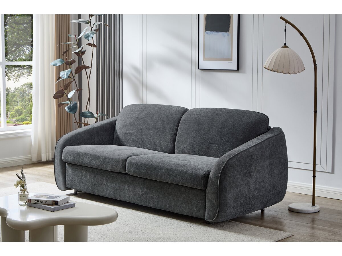 Canapé convertible express moderne, assise double et dossier épais dans un salon lumineux, près d’une lampe arc et d’un plant, prêt pour un couchage quotidien.