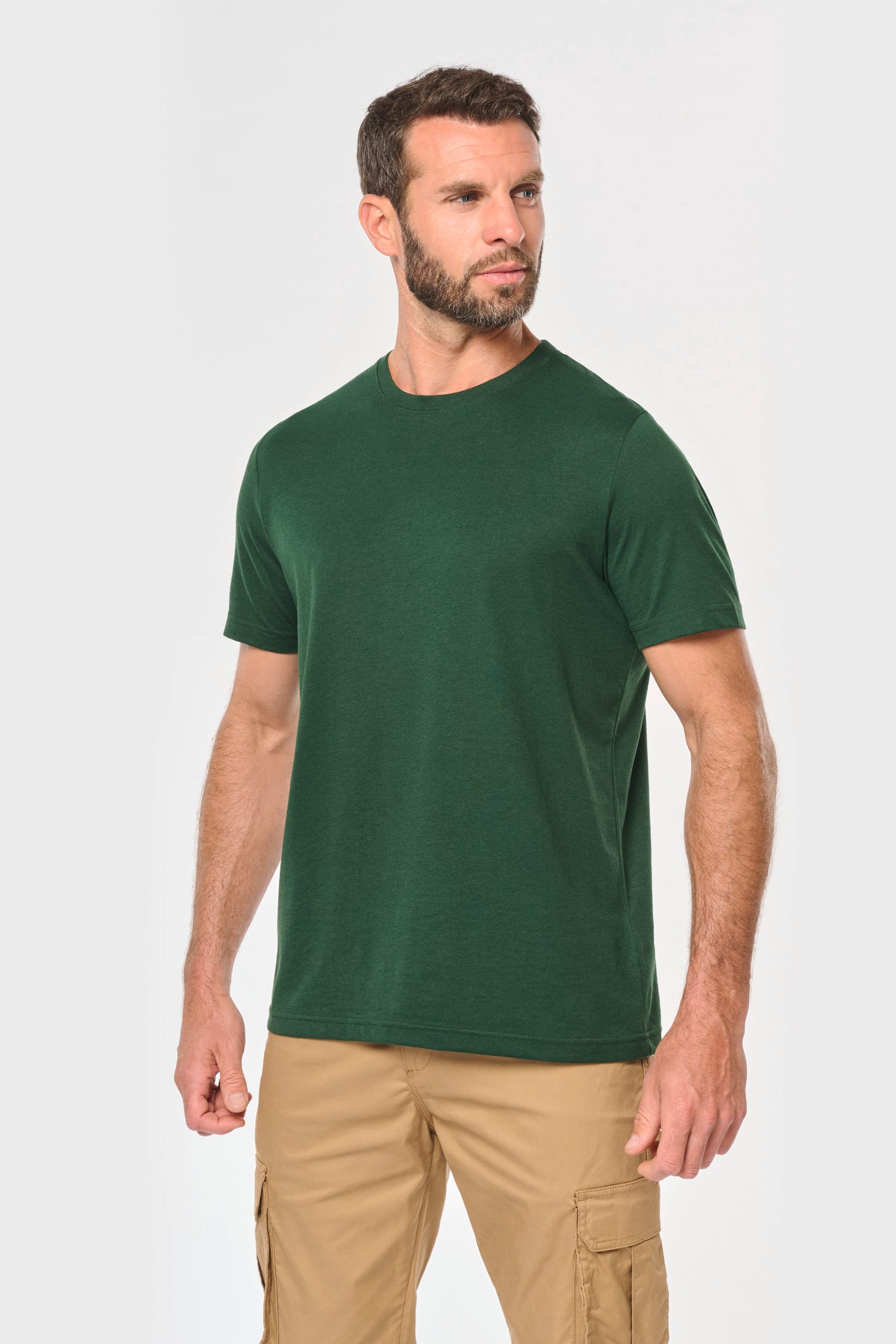T-shirt vert simple porté par un homme, pantalon cargo beige, style décontracté, portrait en contre-jour neutre.