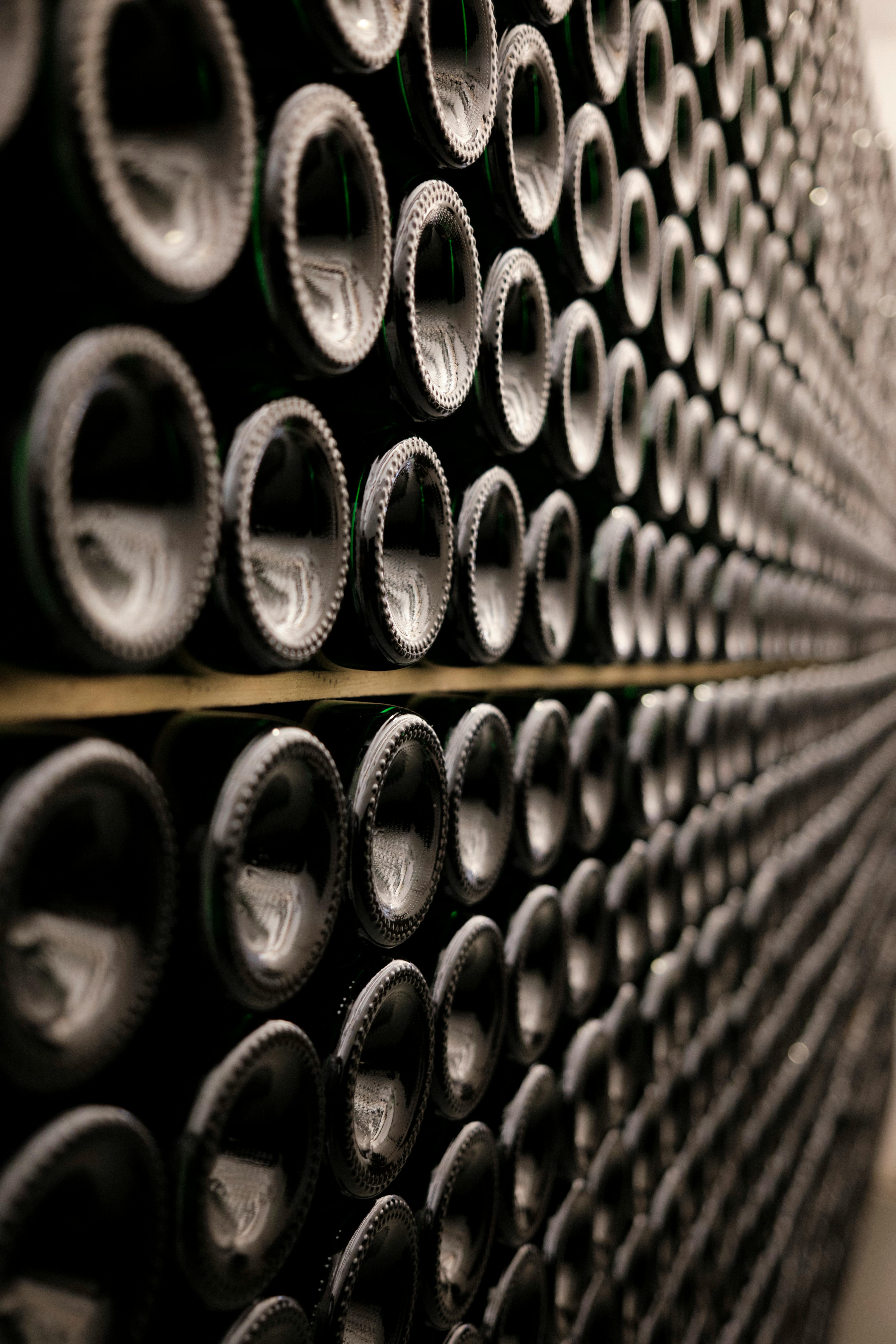 Gros plan de bouteilles de vin alignées dans une cave, illustrant le stockage et la conservation des bouteilles