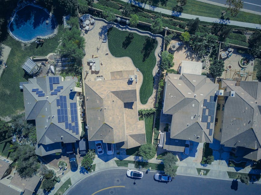 Vue aérienne de maisons suburbaines avec panneaux solaires et pelouses verdoyantes, symbolisant un mode de vie respectueux de l'environnement.