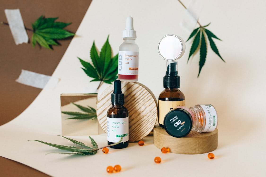 Bouteilles en verre brun d'huiles essentielles posées sur unfond rose, illustrant l'aromathérapie et les soins naturels anti-inflammatoires