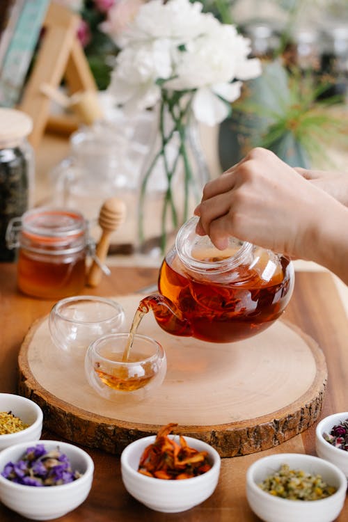 Bocal en verre contenant des fleurs en macération dans de l’huile sur un fond en bois — préparation artisanale de macérât huileux (calendula) pour soin apaisant de la peau.