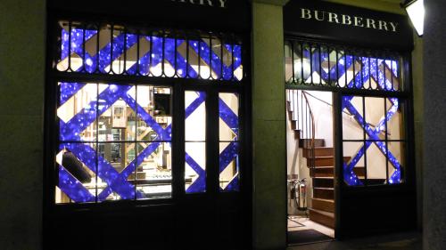 Vitrine de boutique éclairée avec motif bleu et lumineux, affichant des carreaux diagonaux sur les vitres des deux portes.
