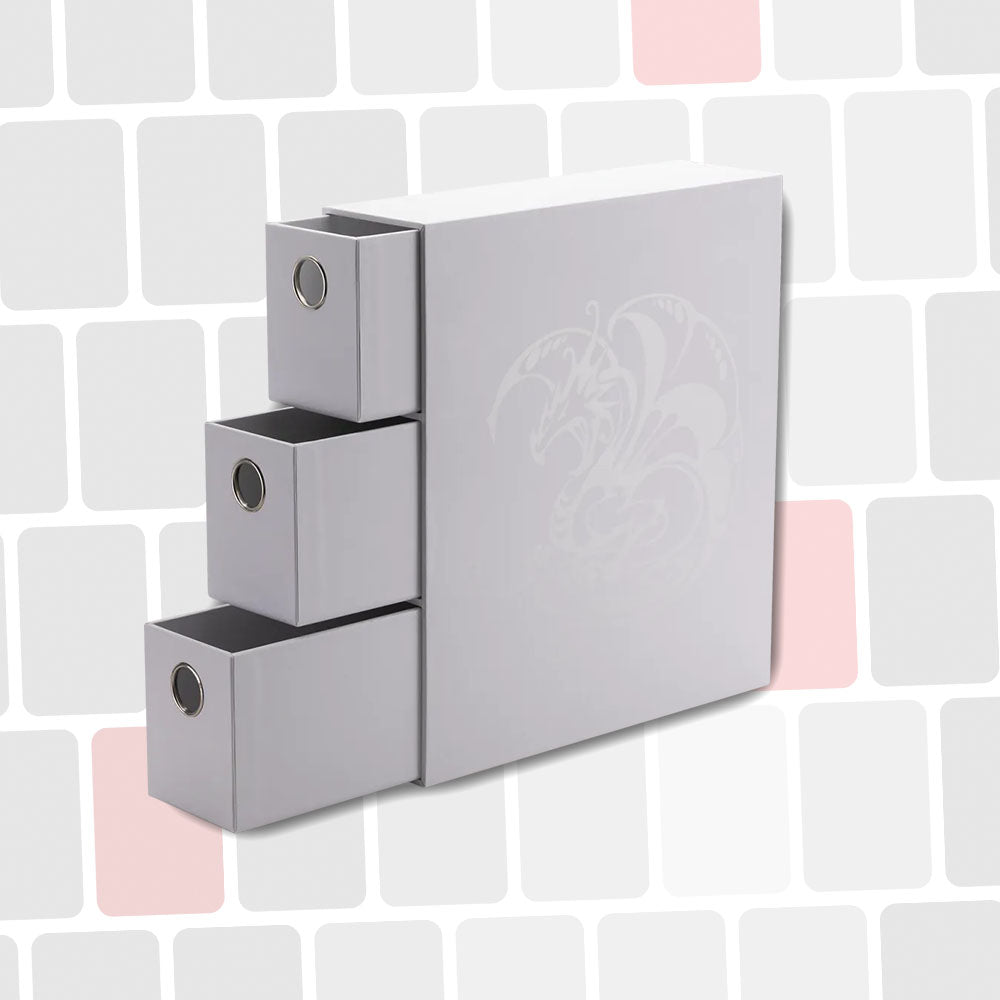 Boîte de rangement gris clair avec trois tiroirs coulissants, logo fantaisie gravé sur le côté, fond de tuiles géométriques.