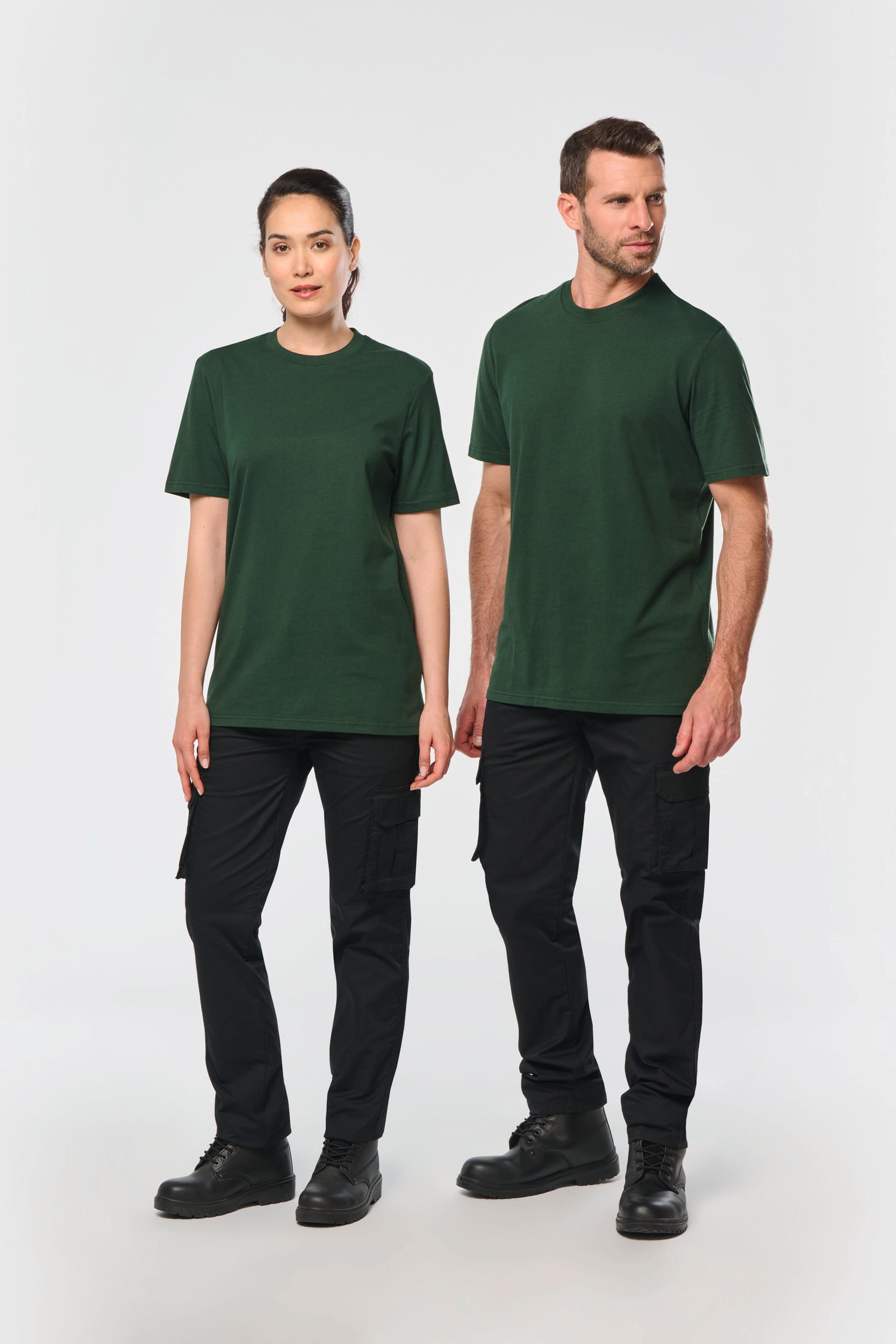 Deux adultes en tee-shirts vert foncé et pantalons cargo noirs, debout, style simple et uniforme.