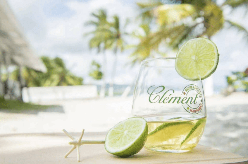Verre de rhum Clément Agricole Martinique avec citron vert, ambiance tropicale en bord de plage