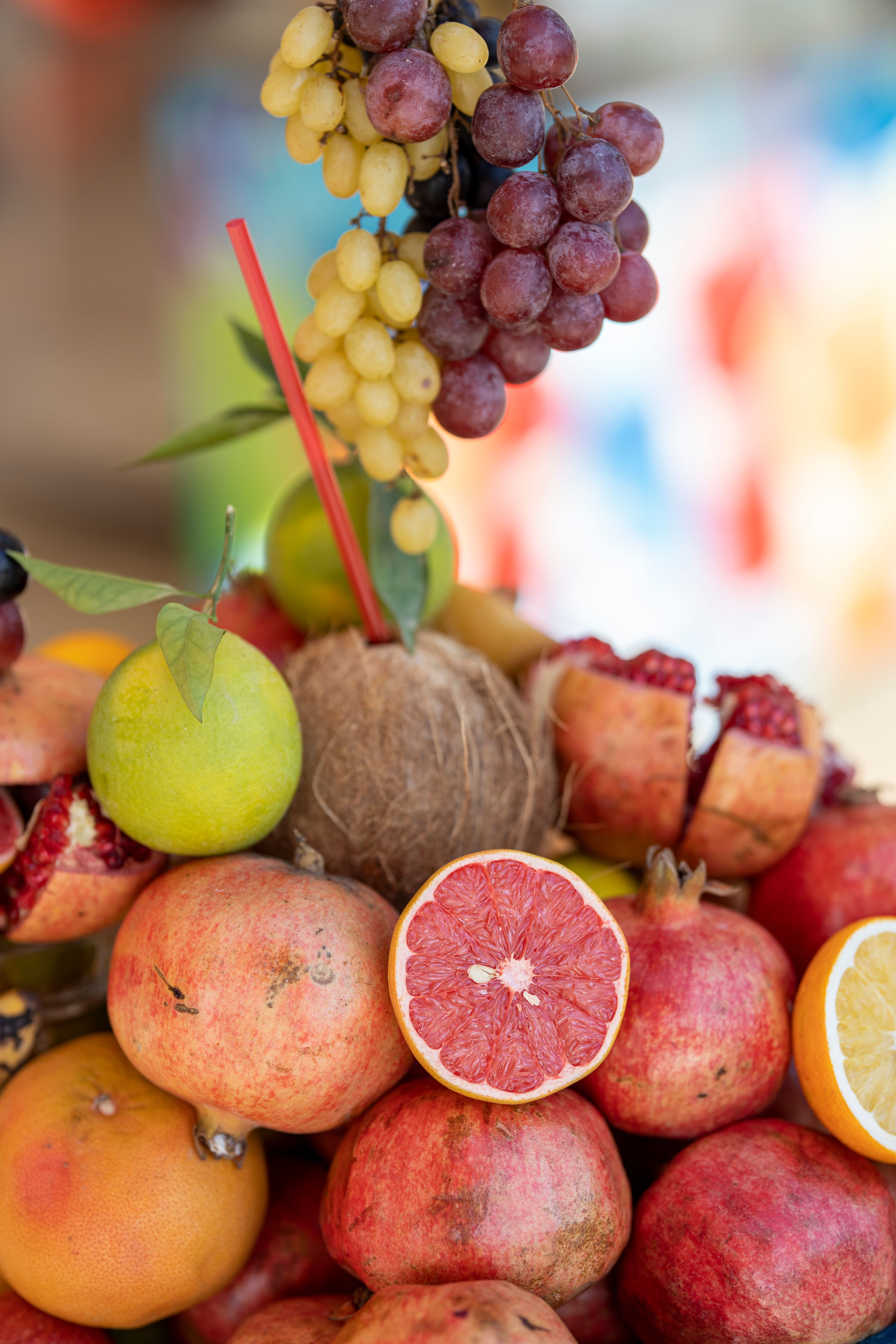 Assortiment de fruits frais, raisin et pomegranate, avec tige rouge et morceaux de fruits coupés pour une touche colorée. Concilier sport et travail suggéré.