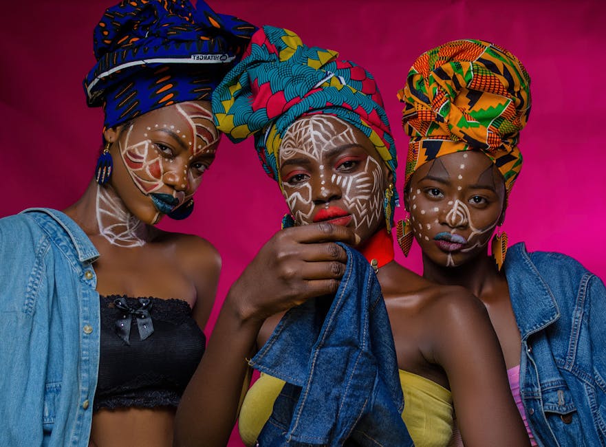 Portrait captivant de trois femmes mettant en valeur la mode africaine avec des foulards colorés et des peintures faciales détaillées.