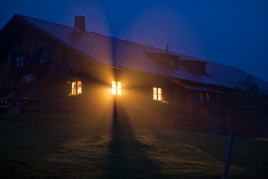 Une lumière chaleureuse émane d'une cabane rustique la nuit, créant une ambiance sereine et accueillante.