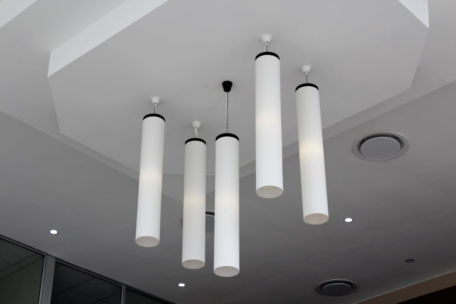 Intérieur moderne minimaliste avec des suspensions cylindriques sur un plafond blanc.
