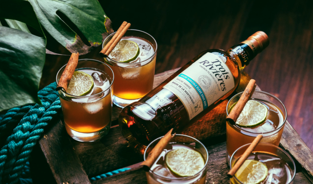 Rhum agricole Trois Rivières de Martinique en bouteille entourée de cocktails au citron vert et cannelle