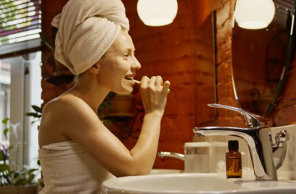 Flacon d'huile essentielle posé sur le rebord d'un lavabo de salle de bain.