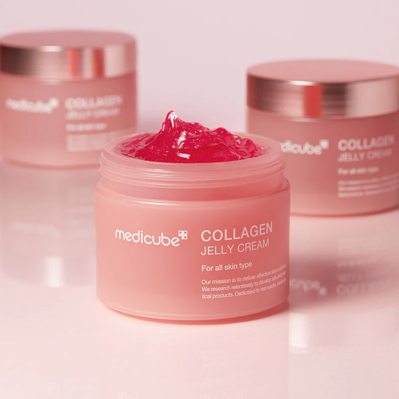 Crème jelly collagène Medicube, pot rose ouvert avec gel vibrant, fond flou montrant d’autres pots similaires. Alt. pas de keyword provided? None. But the context includes K-beauty. If a main keyword provided? Not in user. So generic. Keep 125 chars. Include main subject. Let's craft: "Crème jelly au collagène Medicube dans son pot rose ouvert, posé sur une surface rose, flacons similaires en arrière-plan." Crème jelly au collagène Medicube dans son pot rose ouvert, posé sur surface rose avec d’autres pots en arrière-plan.