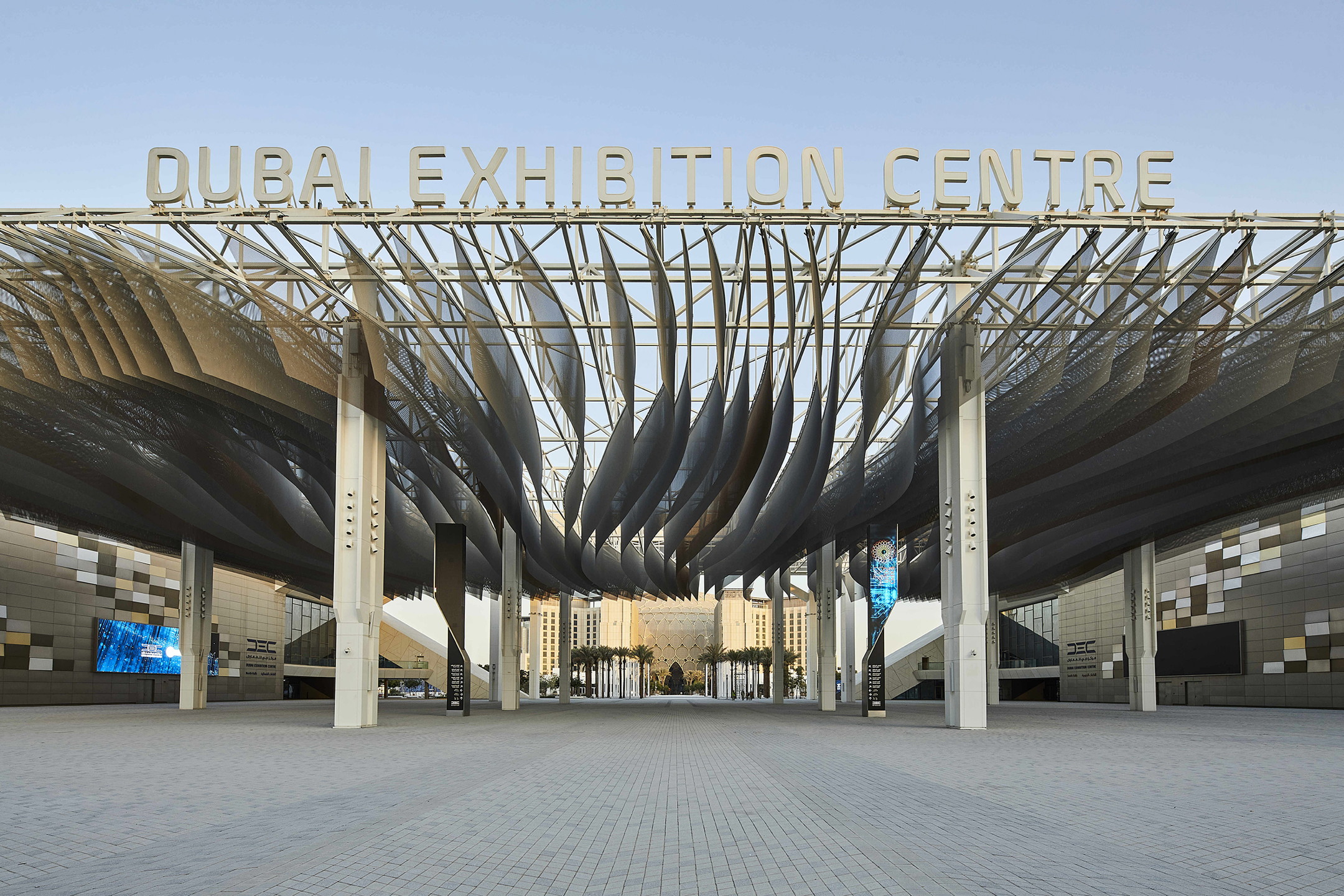 Écran LED géant installation extérieur dans un centre d’exposition, façade moderne avec auvent sculptural et espaces ouverts.