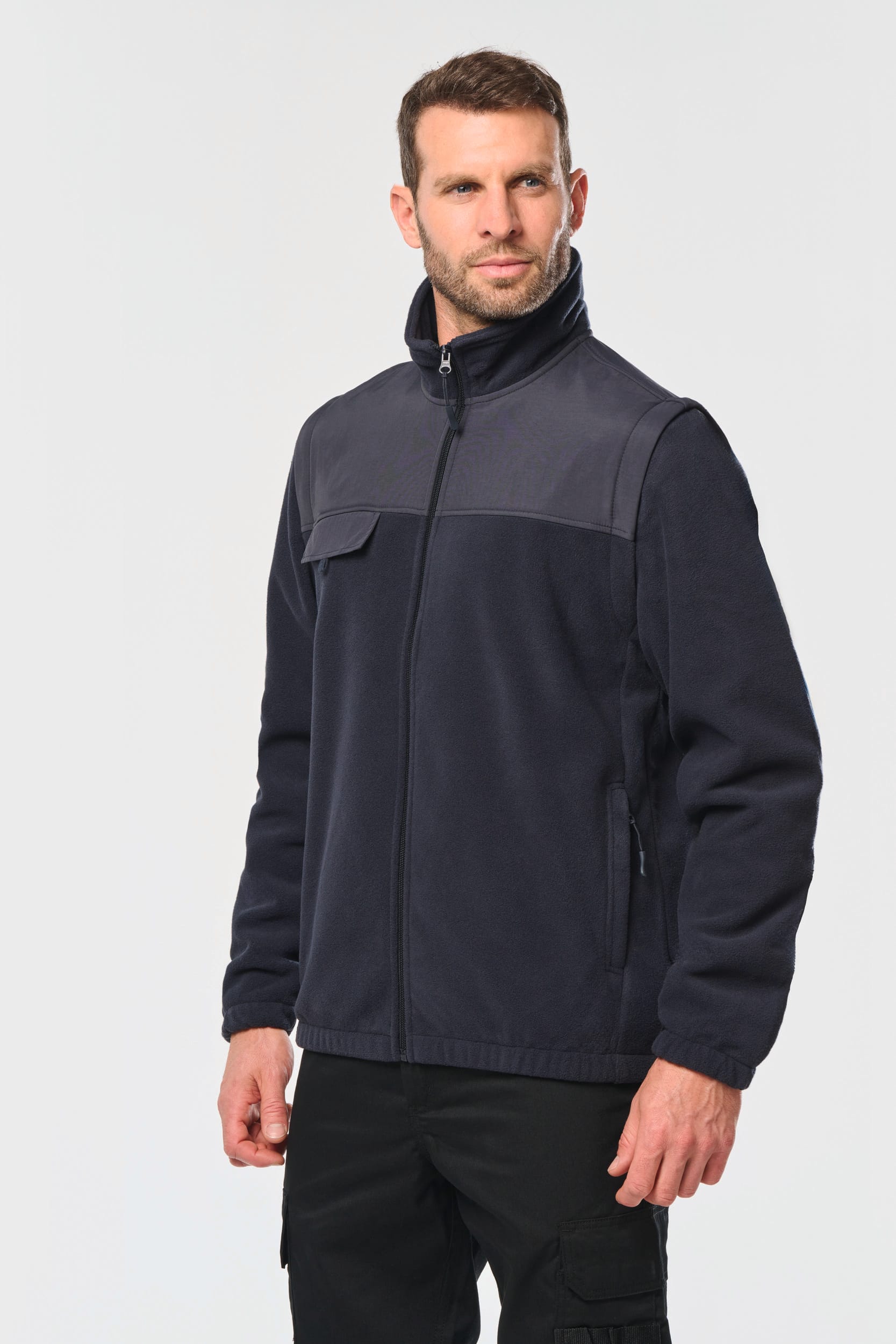 Homme portant une veste légère bleue marine à col montant et poches zippées, posé de face.