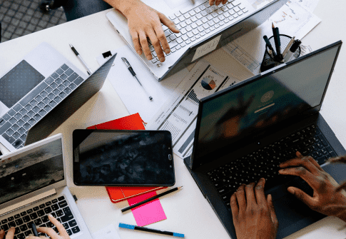 Gros plan sur des ordinateurs portables et une tablette sur un bureau; documents, stylos et carnets, ambiance travail et enquête. Comment prouver un détournement de fonds, contexte successoral.