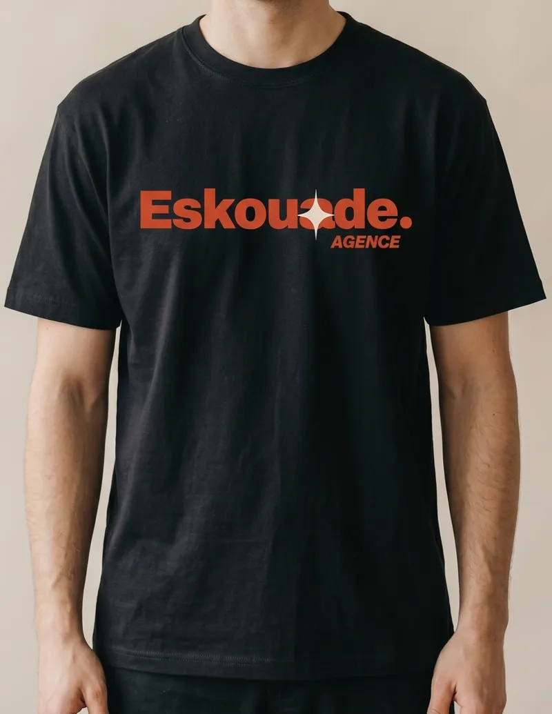 T-shirt noir avec logo orange "Eskoude" sur le torse, vue poitrine, mannequin masculin de face. Indique un objet personnalisé entreprise.