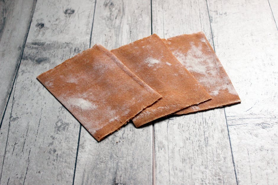 Trois feuilles de papier abrasif disposées sur une surface en bois rustique, idéales pour les projets de bricolage.