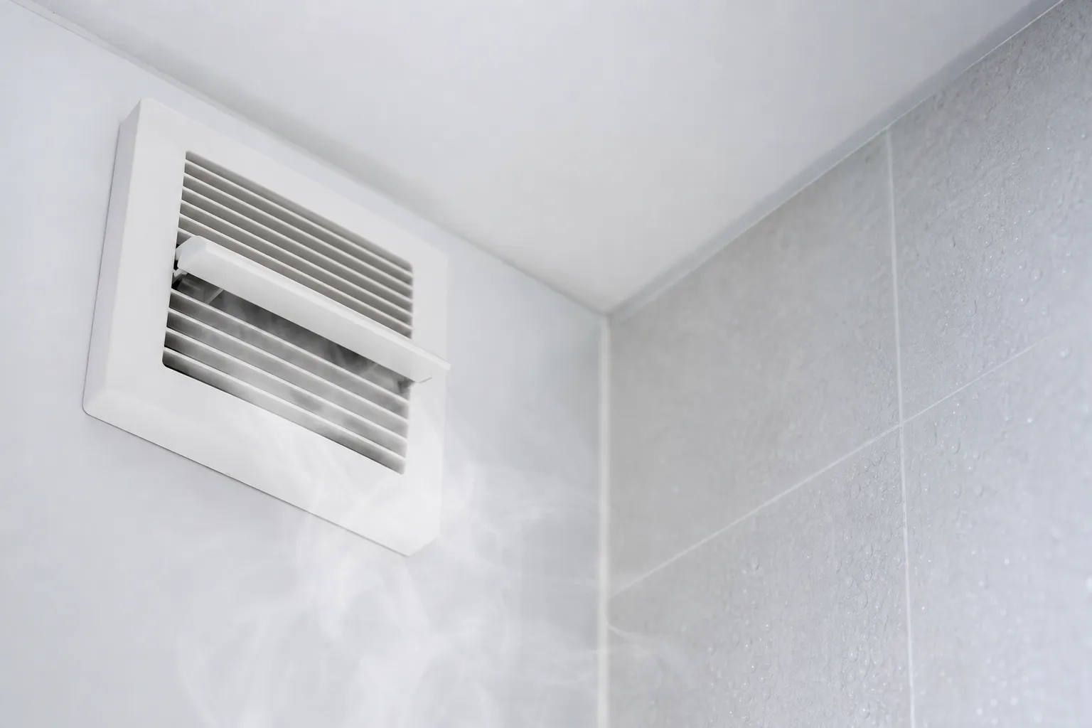 Grille de VMC dans une salle de bain émettant de la vapeur d’humidité, illustrant à quoi sert une vmc dans une salle de bain.