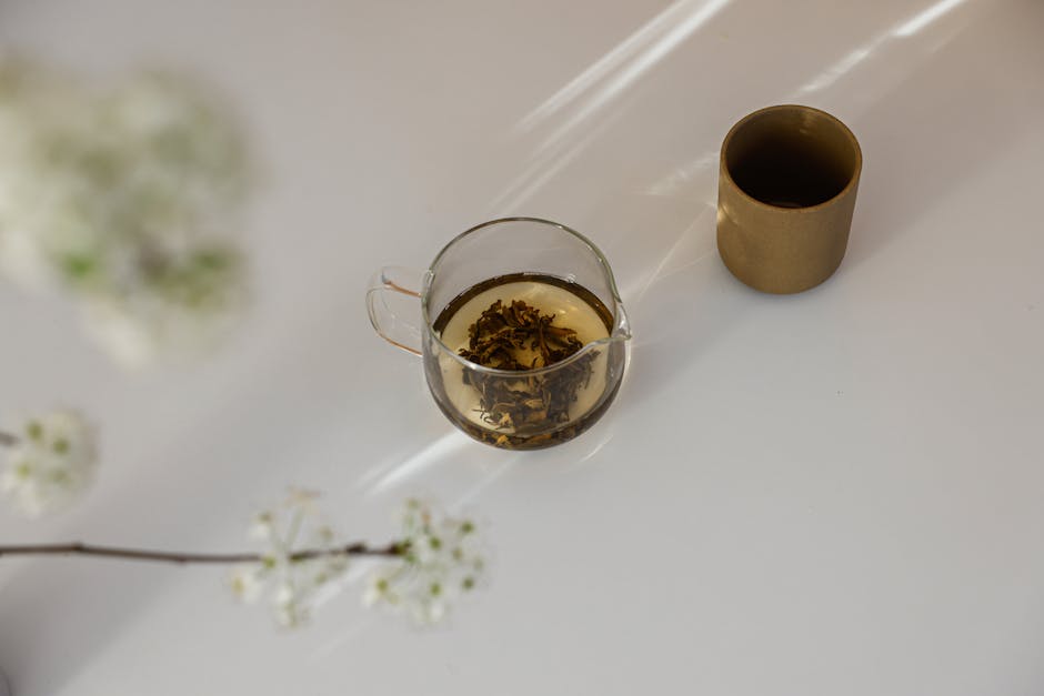 Tasse de tisane aux herbes accompagnée de fleurs dans un cadre minimaliste et apaisant.