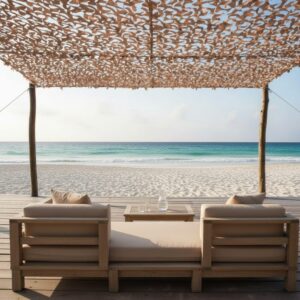 Deux fauteuils et table basse sous un store camouflage au bord de la plage, vue sur la mer et le sable. Bien choisir son brise-vue n'est pas nécessairement lié ici.
