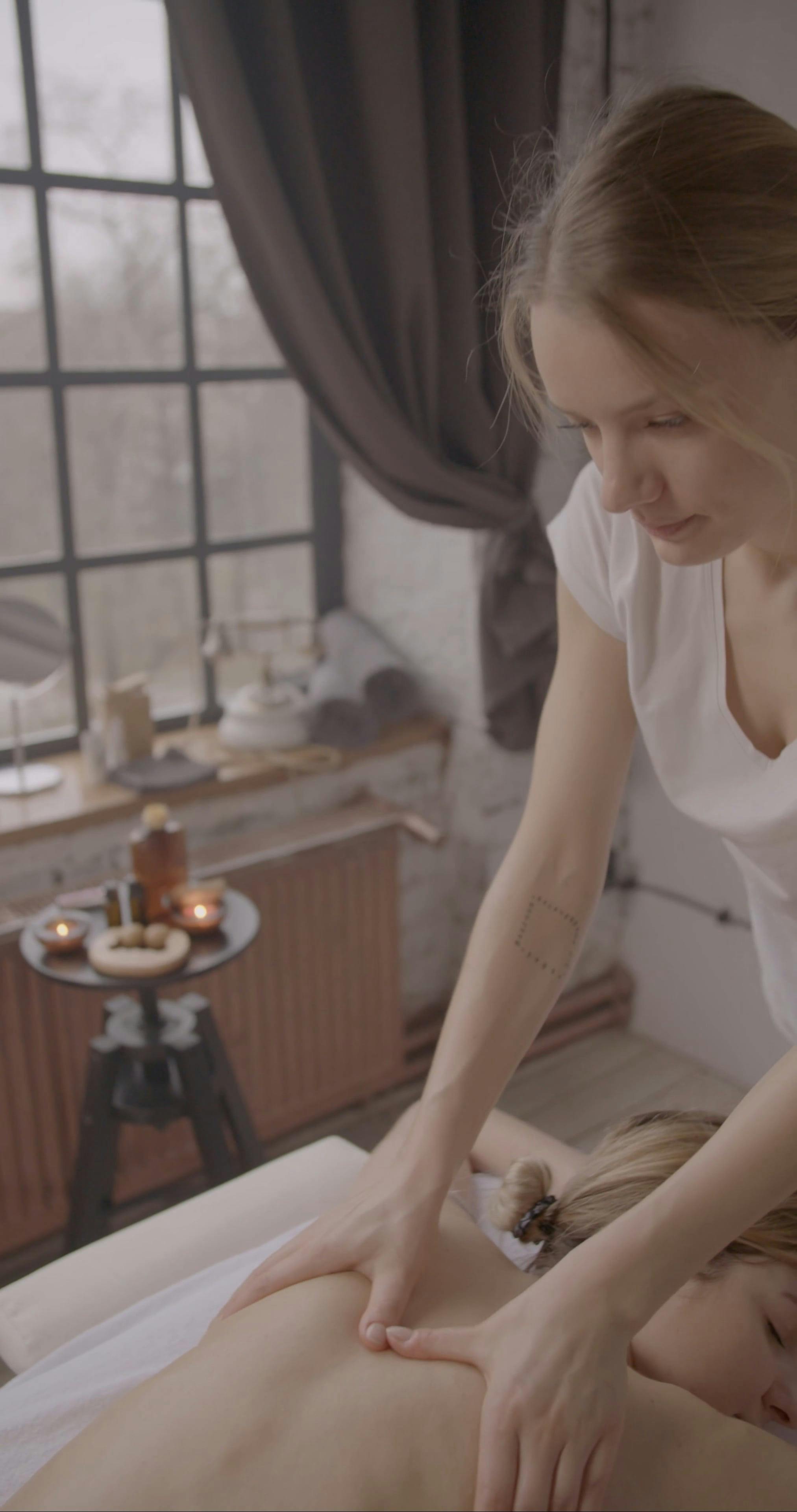 Gros plan d’un massage du dos à l’huile essentielle : mains du thérapeute appliquant une huile aromatique sur le bas du dos dans une ambiance calme et relaxante.