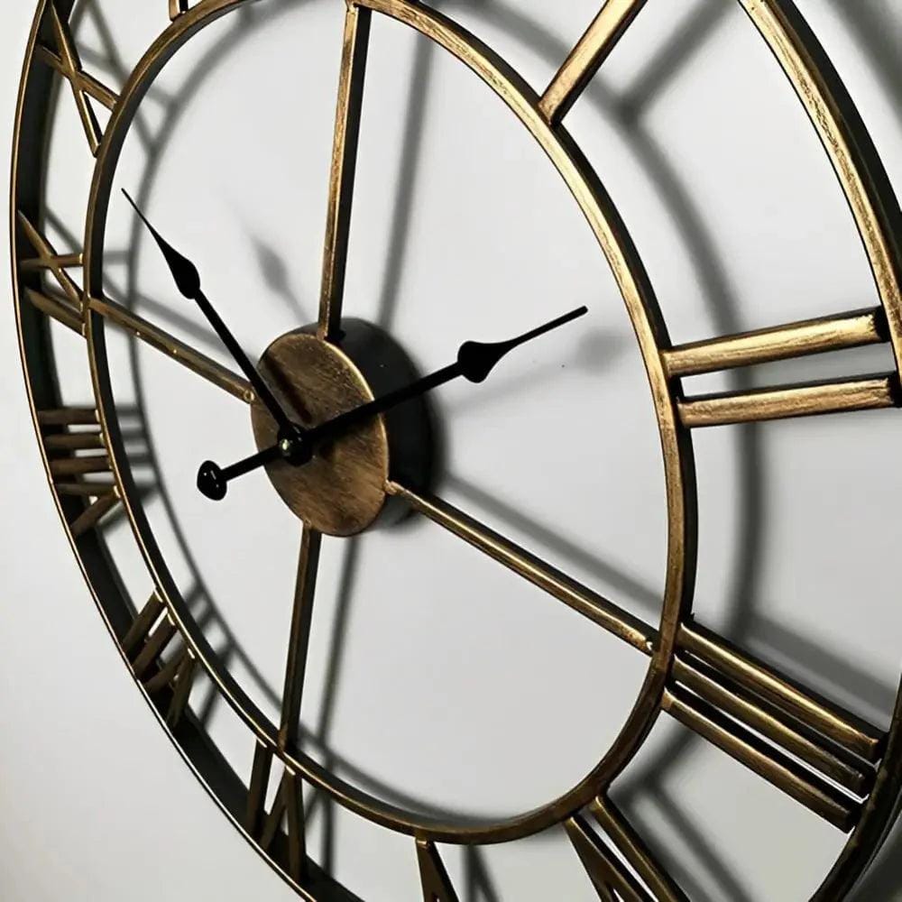 Horloge murale en métal doré avec chiffres romains, cadran ouvert et aiguilles noires, style industriel chic.