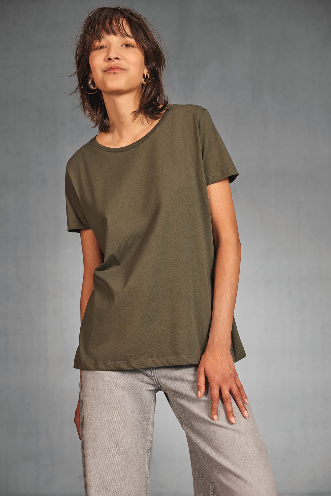 T‑shirt oversize personnalisé sans étiquette, simple coupe ample kaki porté par une femme, pantalon gris clair.